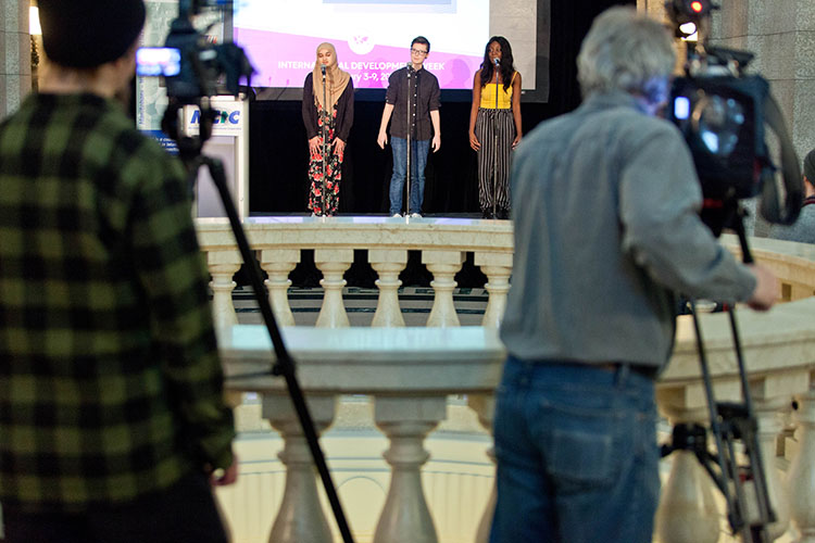 Three young people preparing to perform a play are filmed by two cameramen.