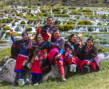 A group of women wave by a stream in Peru