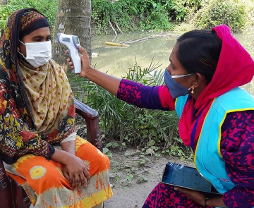 A community health worker in Bangladesh takes a patient’s temperature
