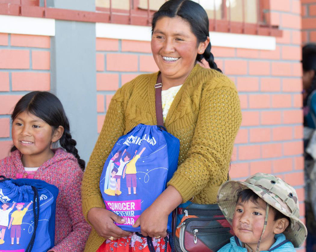: A pregnant woman and toddler smile at the camera.