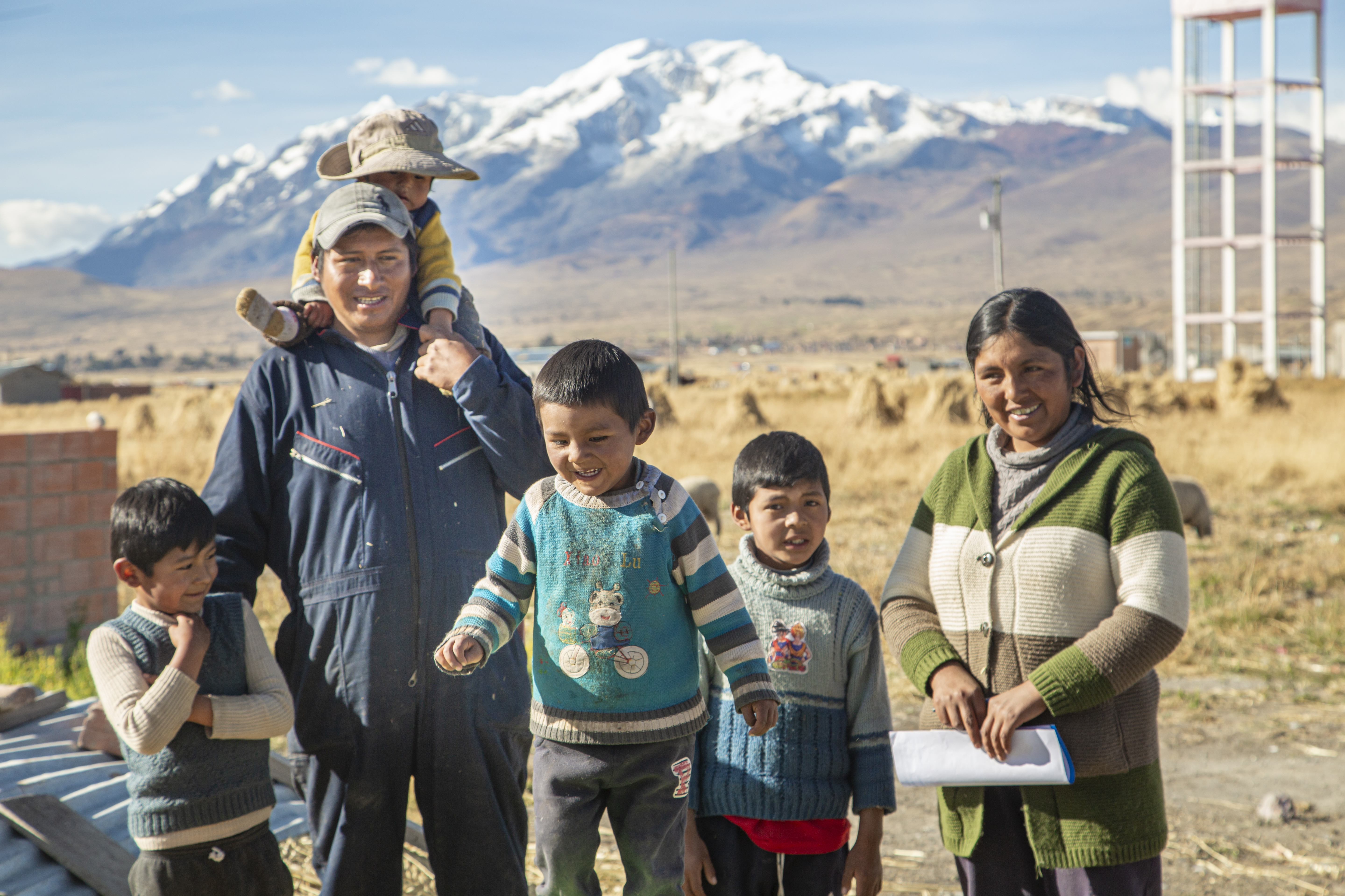 A woman stands in front of a beautiful mountain with her husband and 4 young boys.
