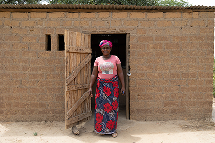 Annie standing in front of an open door of her home.